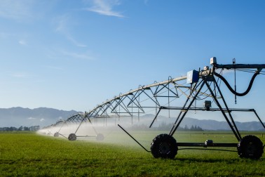A pivot irrigator spraying water over farmland