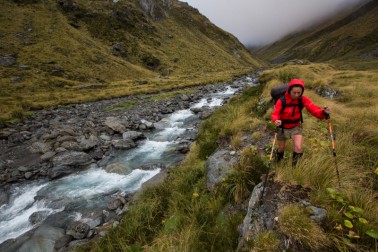 A hiker walking along a stream on Stewardship land