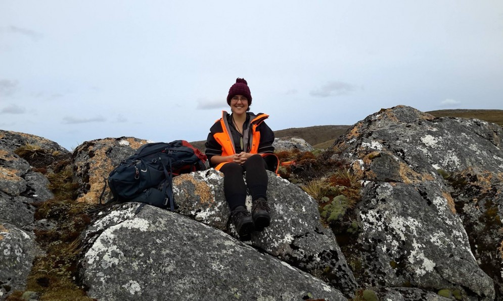 Sam Lincoln sitting on a rock in Rakiura