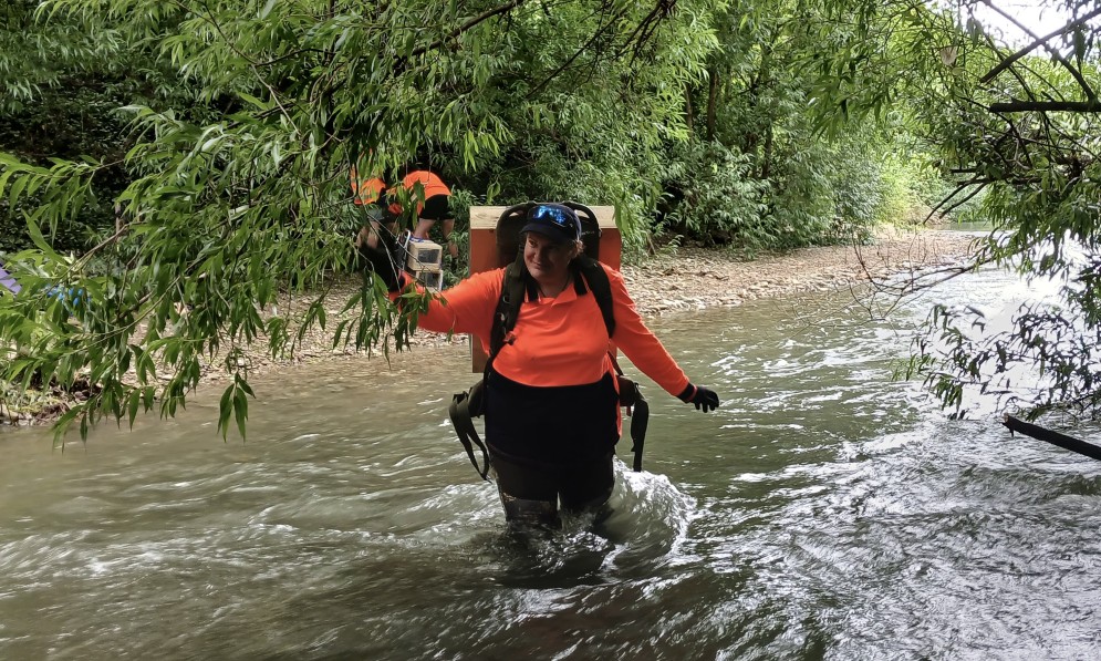 Former Te Hoiere team member Jessica Armstong crosses a river in Ronga Reserve to set up a new trapline. Image Forest & Bird