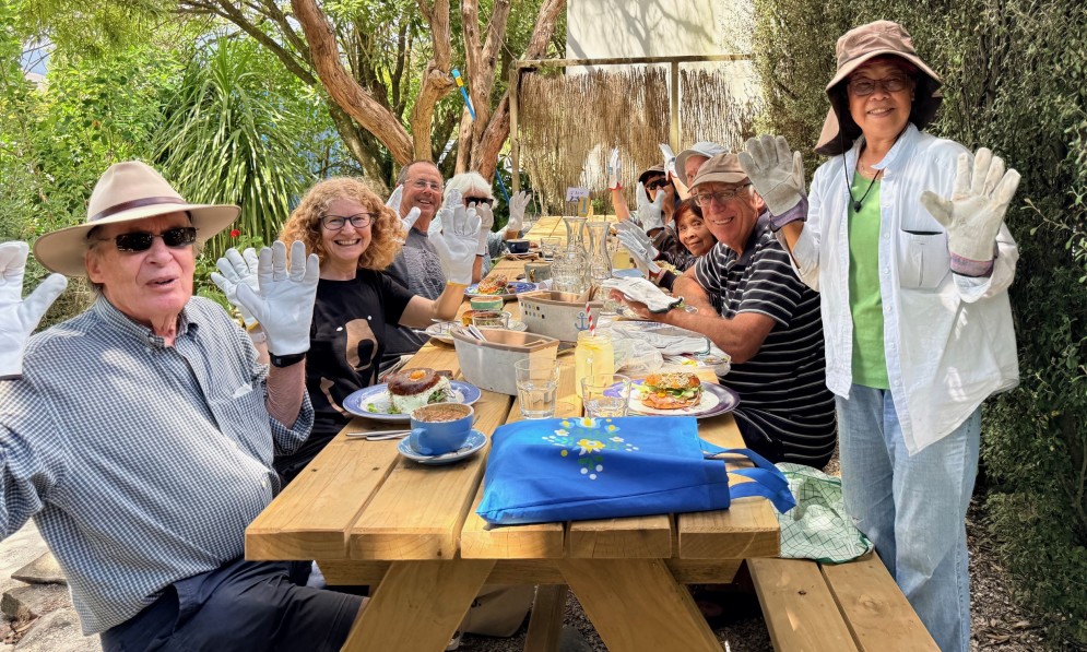 People around a table, holding up their hands wearing white weeding gloves