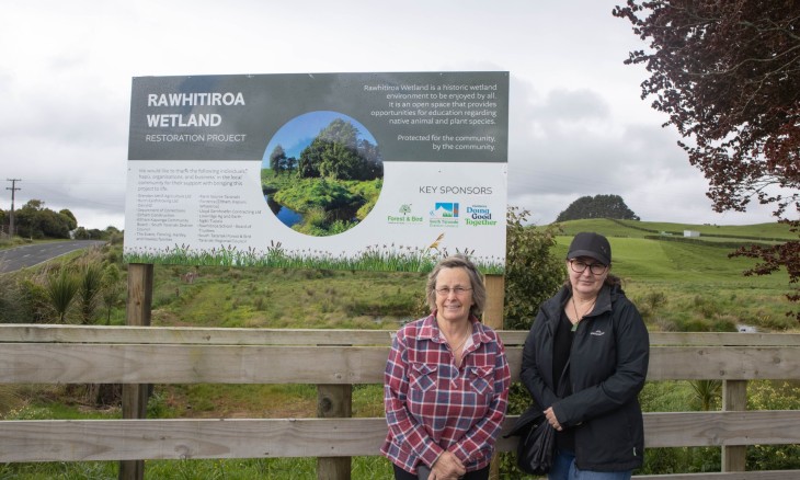 Two people standing by the wetlands.
